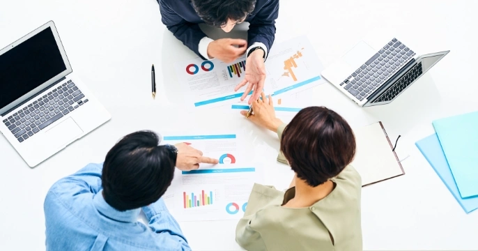 男女3名が机を囲んで相談している